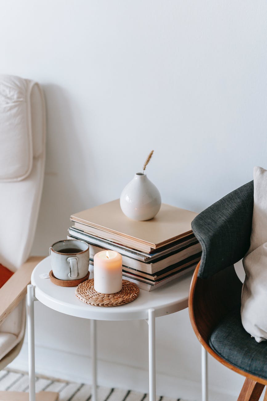 table with tea and flaming candle between armchairs in room